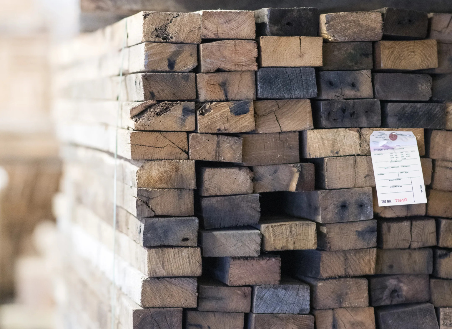 A stack of salvaged oak timbers showing weathered end grain in gray and brown