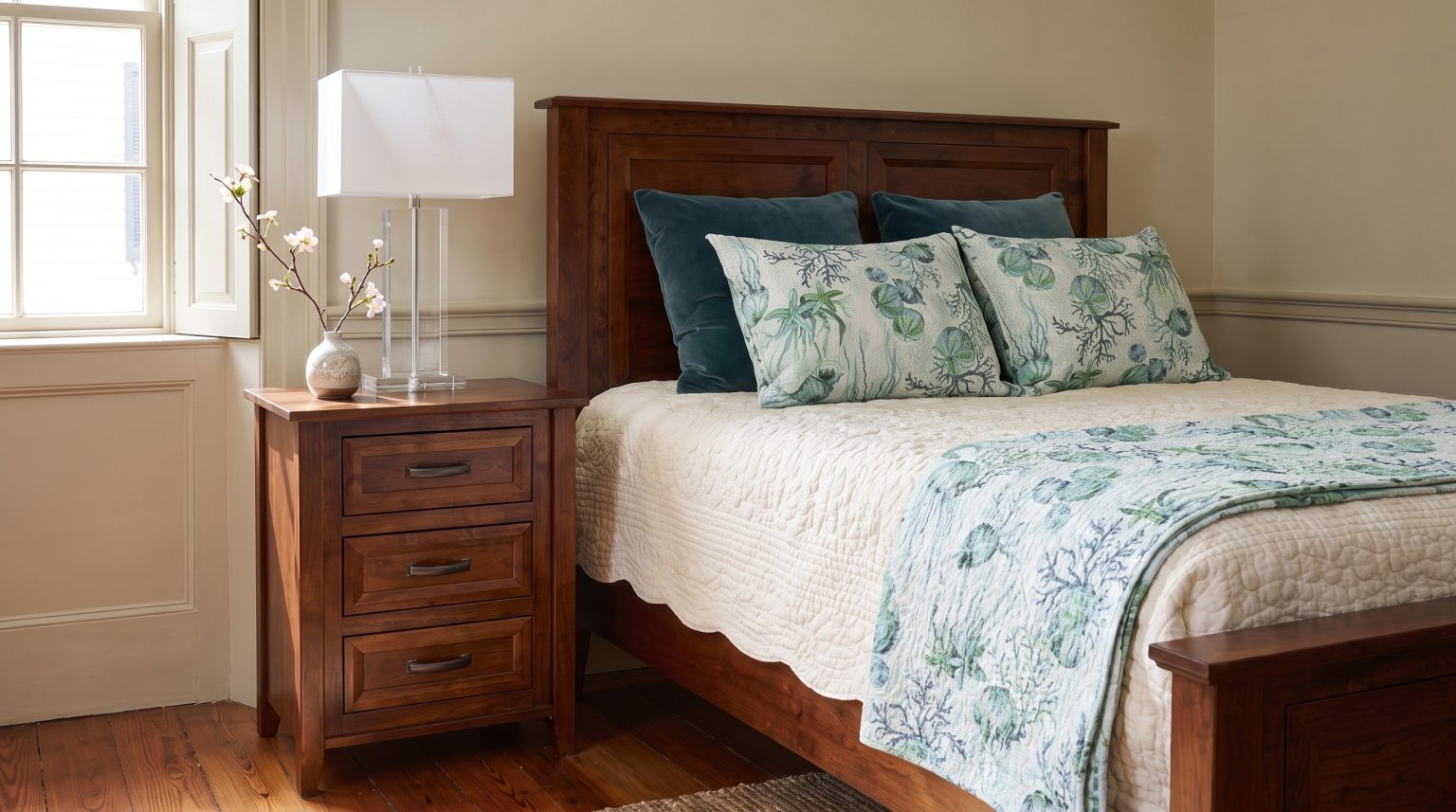 Headboard and nightstand: The paneled cherry headboard beside the three-drawer stand.