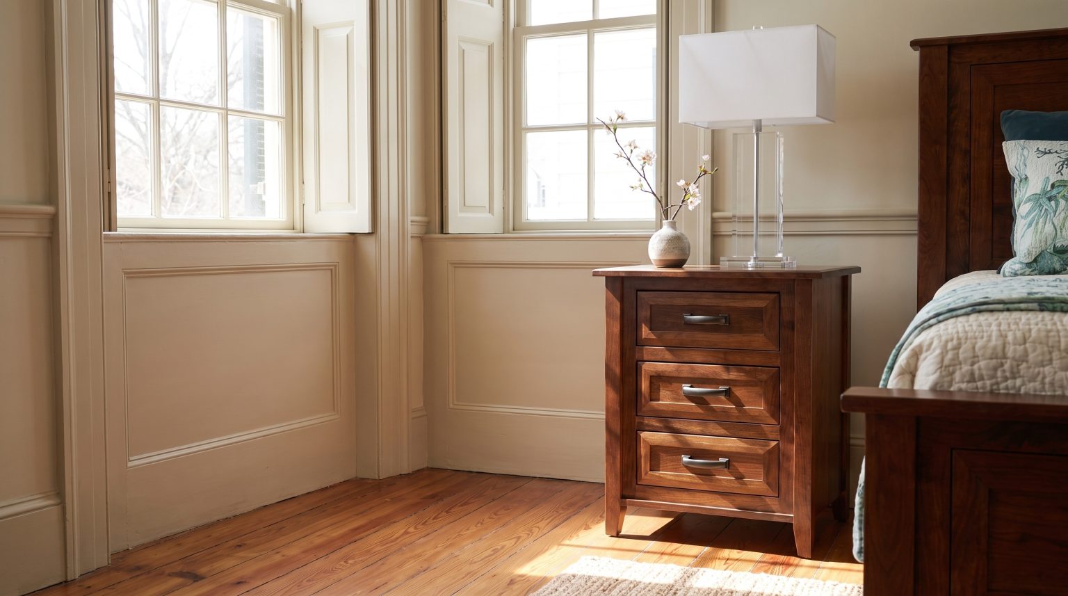 The cherry nightstand: Three drawers with dark bronze bar pulls.
