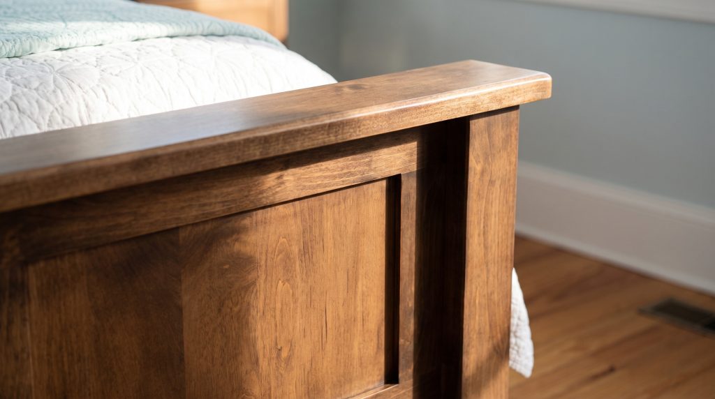 Footboard corner: A recessed panel meeting a square post and flat top rail.