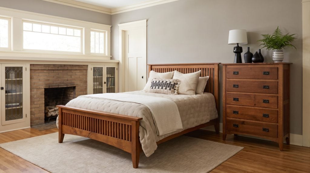 A quartersawn oak Mission bed with vertical slats on headboard and footboard, and a matching five-drawer chest with black iron pulls, in an Avondale bungalow in West Ashley.