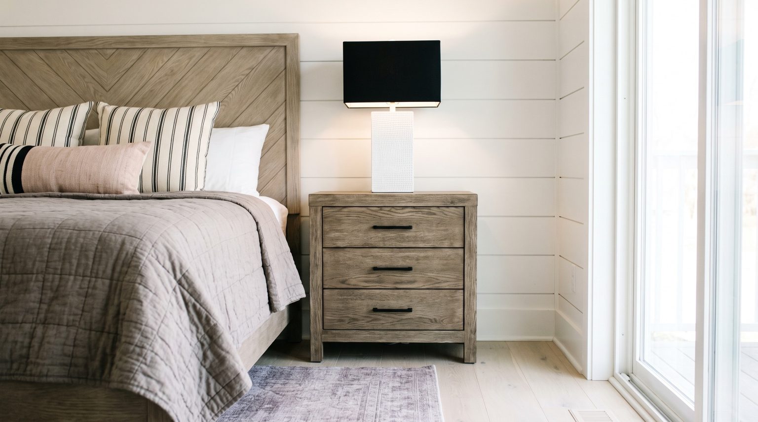 Chevron headboard and nightstand: Diagonal planks behind the pillows, beside the three-drawer stand.