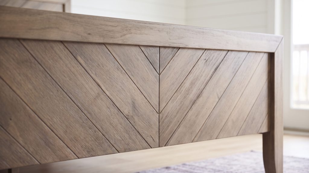The chevron: Diagonal oak planks meeting in a V at the headboard center.