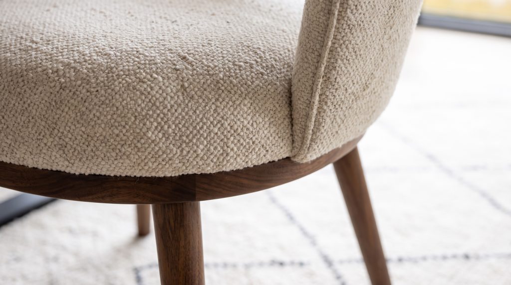 Boucle on walnut: Nubby oatmeal boucle meeting a tapered walnut leg.