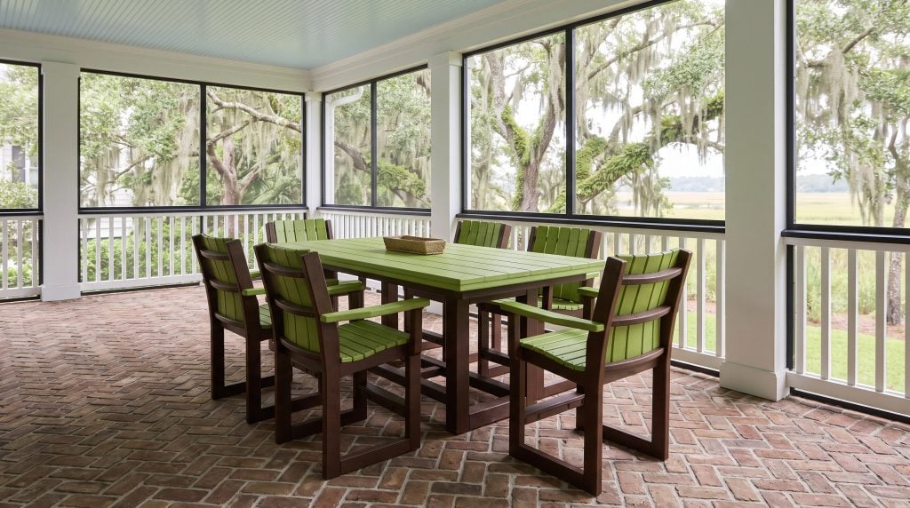A poly lumber dining set with a lime green slatted top and six lime and dark brown sled-side armchairs on a Kiawah screened porch with a haint-blue ceiling.