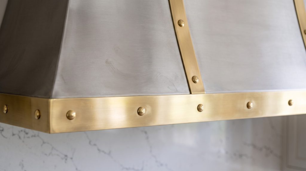 Brass on steel: A brass strap and riveted band on the brushed hood.