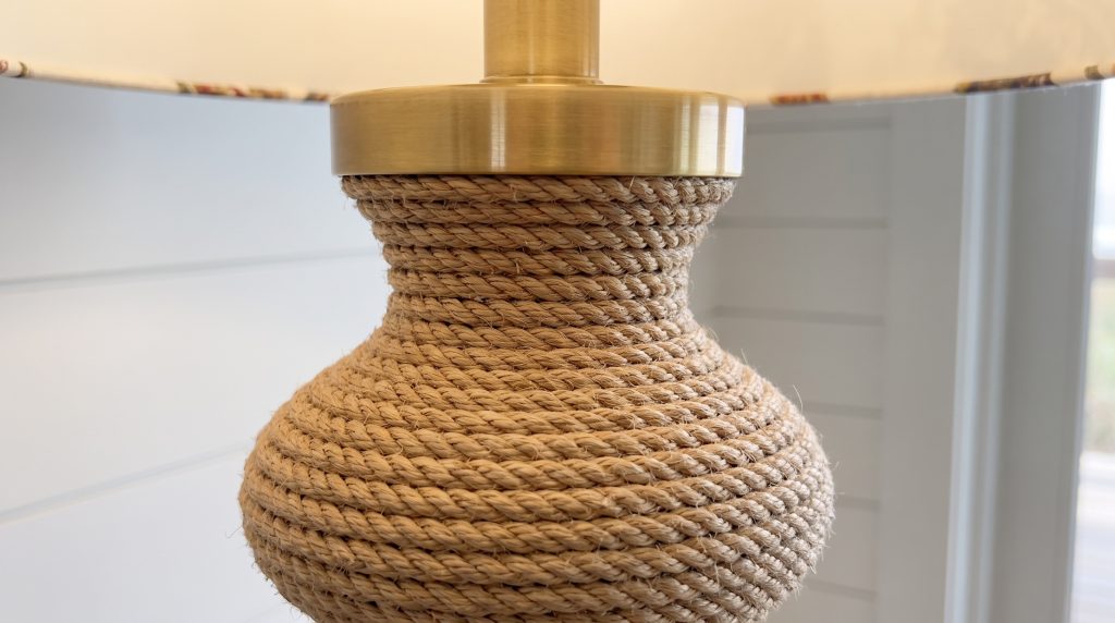 A close view of twisted rope laid coil against coil around a lamp body, meeting a polished brass collar