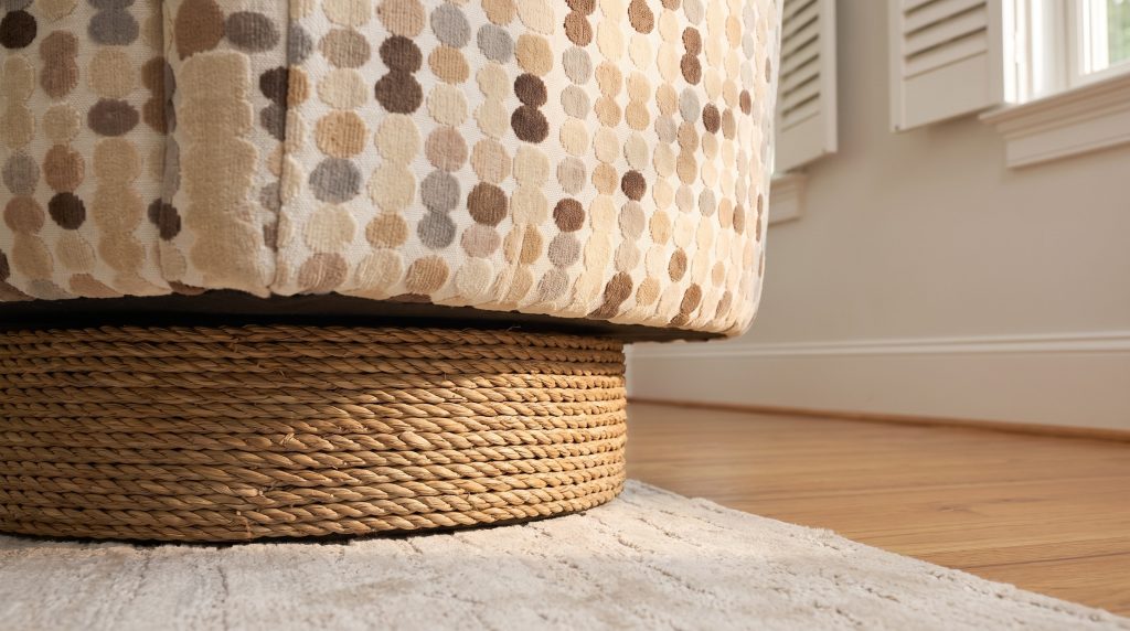 A close view of the dotted upholstery of a swivel chair meeting its coiled seagrass rope drum base