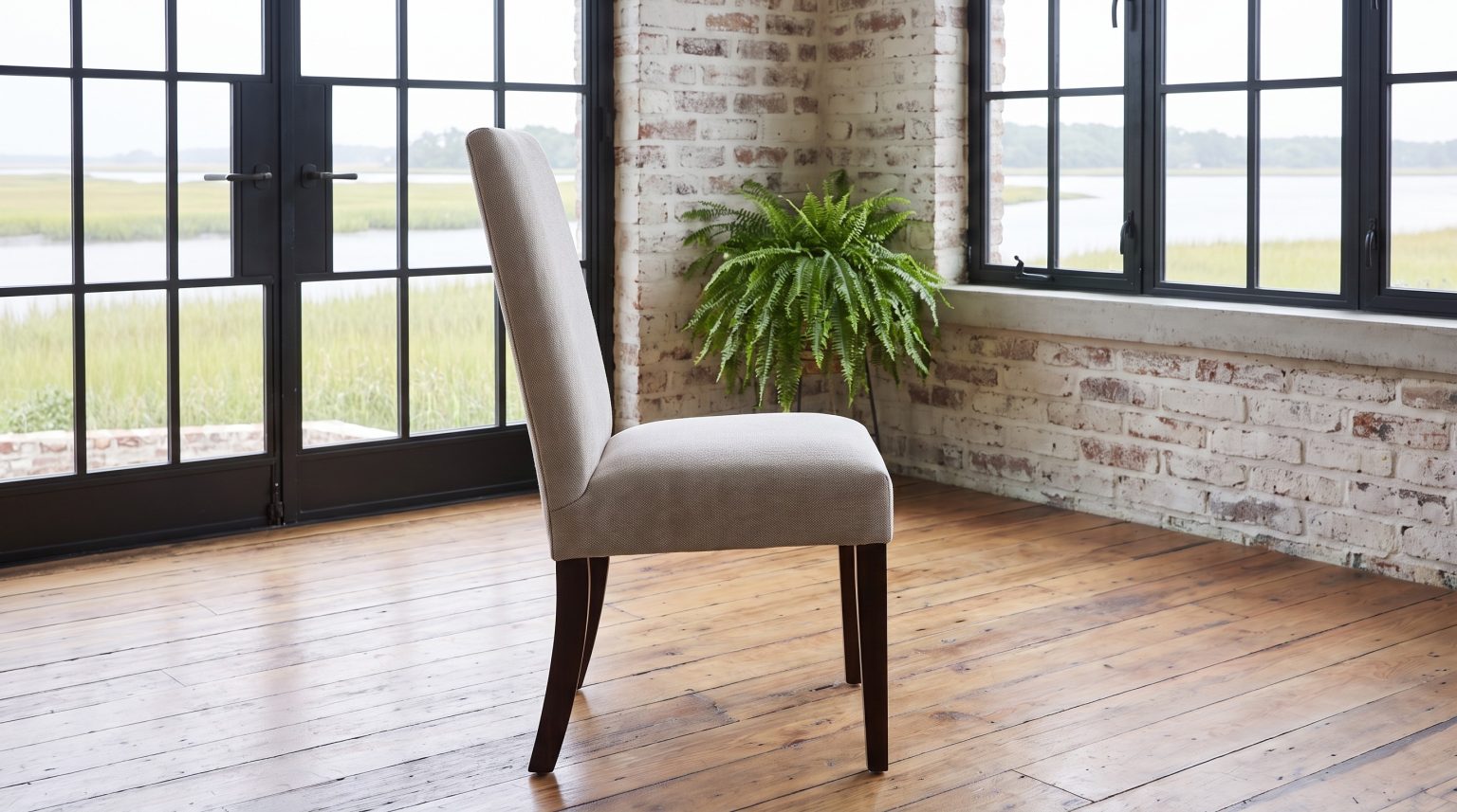A tall upholstered parsons chair in pale greige woven fabric on near-black tapered legs