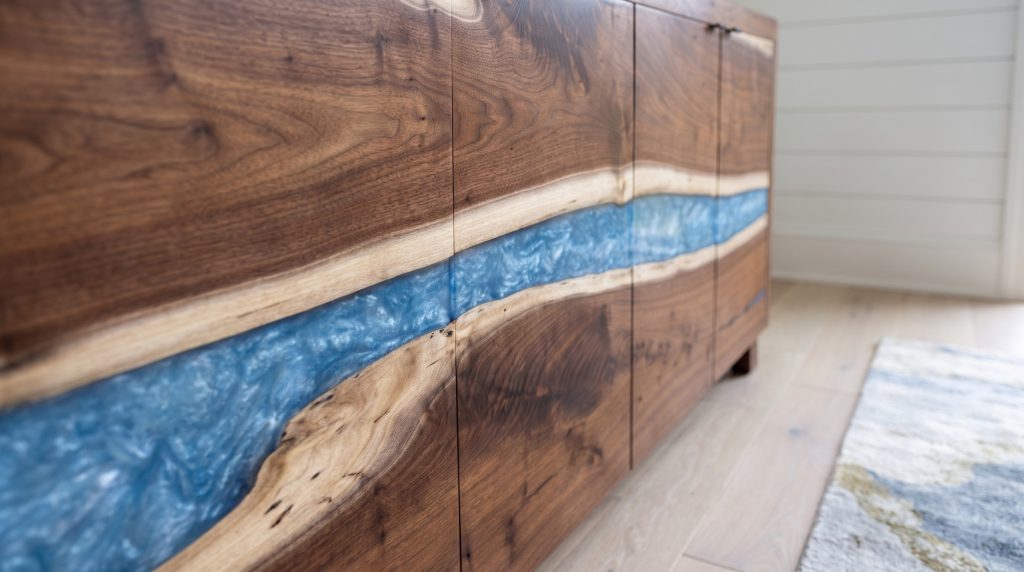 A close view of translucent blue resin flowing between the pale sapwood live edges of dark walnut door panels