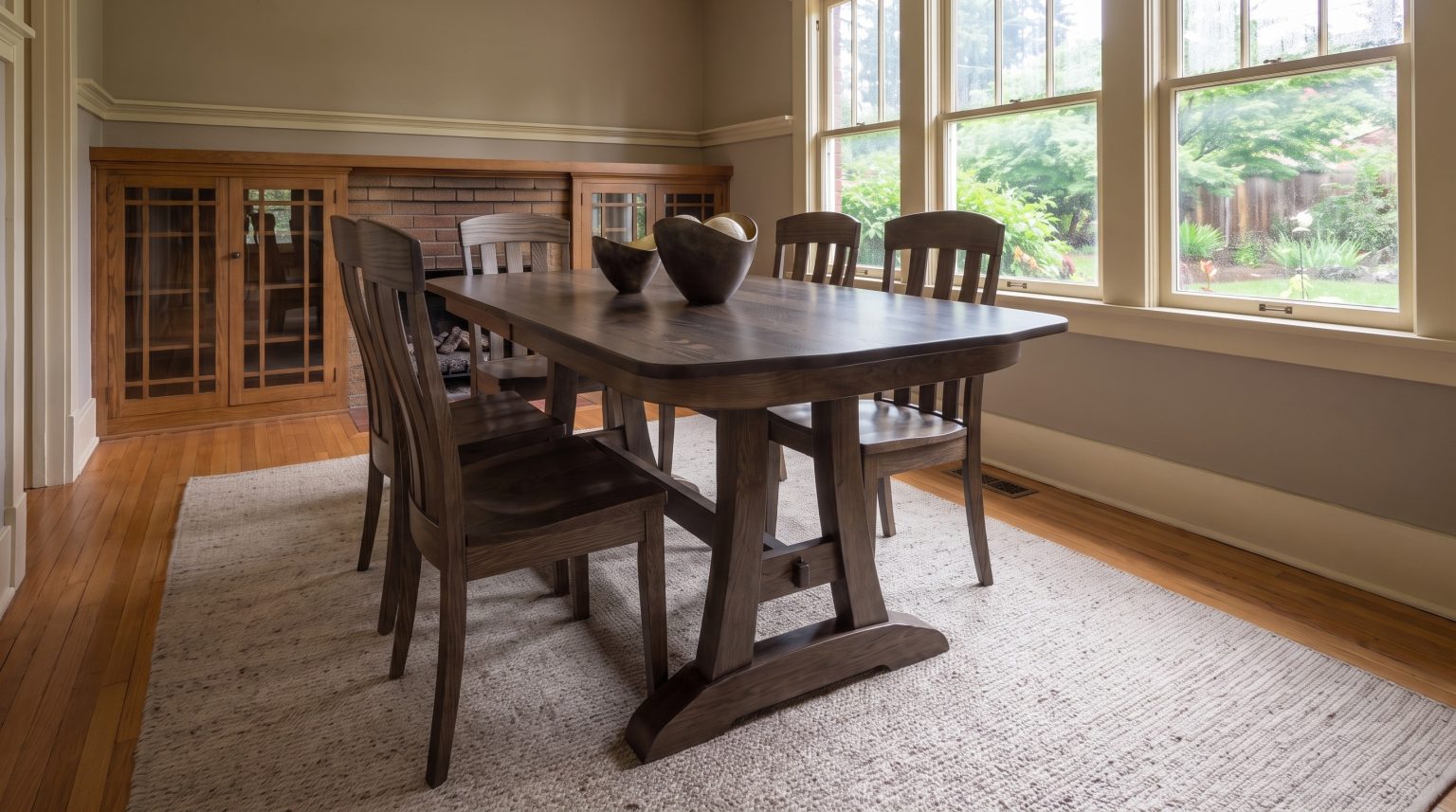 A shadow-stained oak trestle table showing plank pedestals on splayed feet joined by a low stretcher