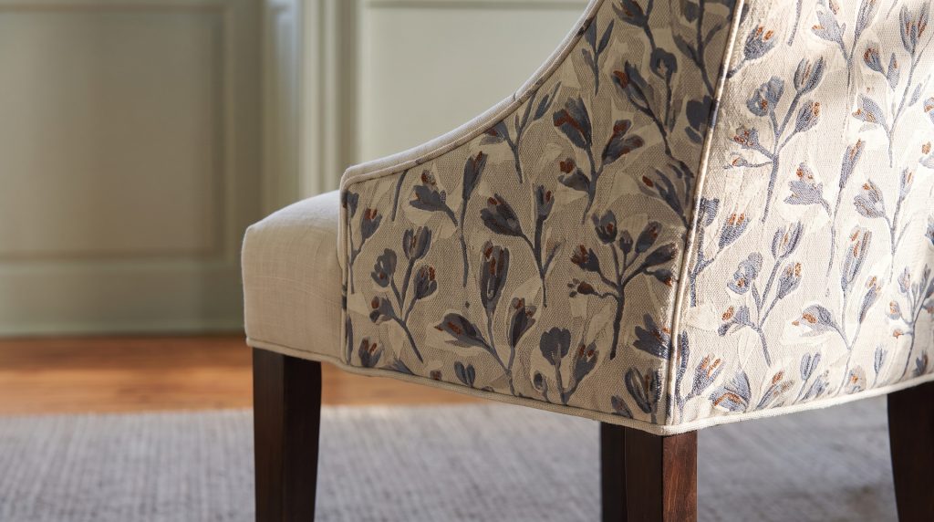 A close view of a floral chair back in slate blue and rust wrapping to ivory linen