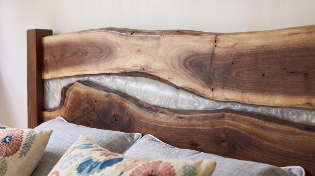 A close view of pearl-white resin flowing between the live edges of two walnut slabs