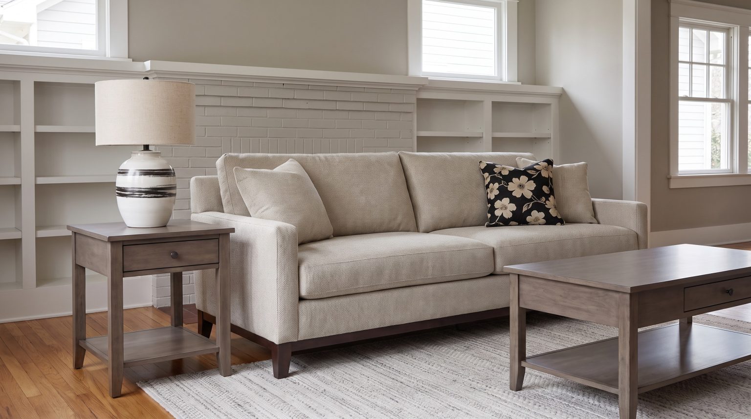 An oatmeal track-arm sofa with a smoke maple end table and coffee table in front of white built-ins