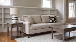 An oatmeal track-arm sofa with a smoke maple end table and coffee table in front of white built-ins