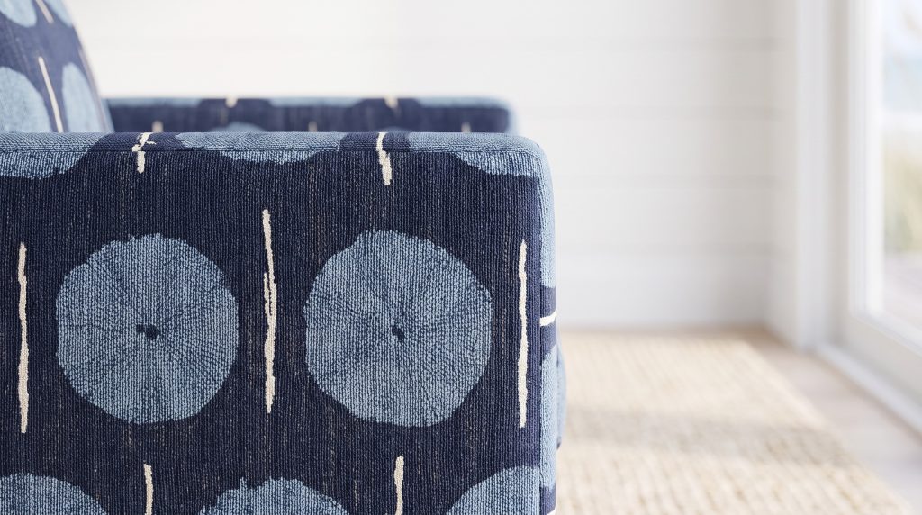 A close view of a navy chair arm printed with sky-blue medallions and cream stem lines