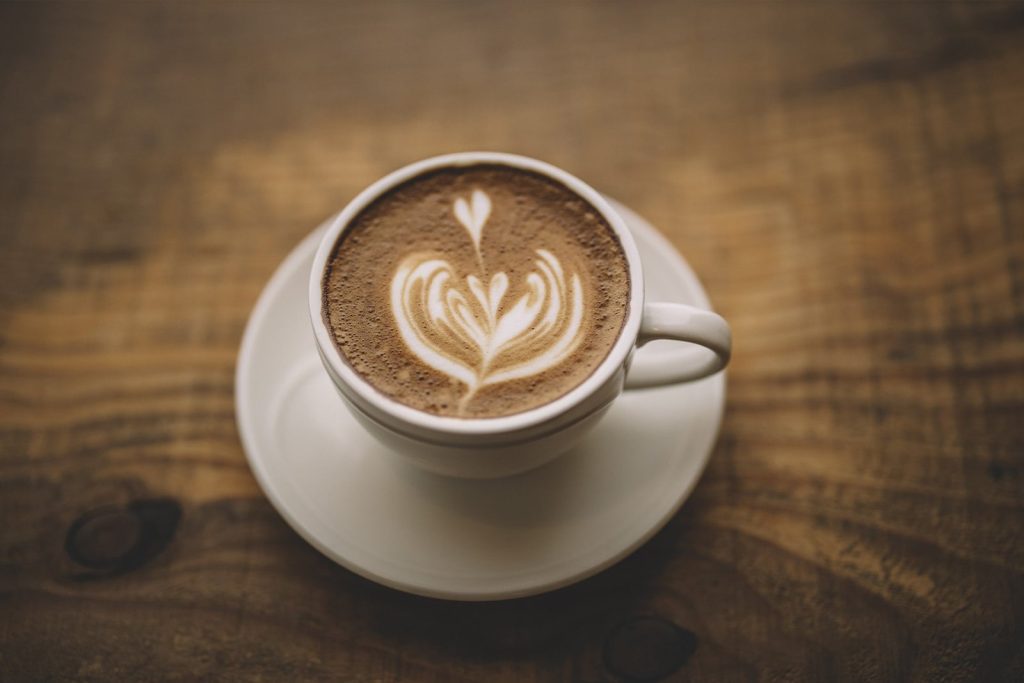 A coffee cup on a coaster on a solid wood Amish dining table