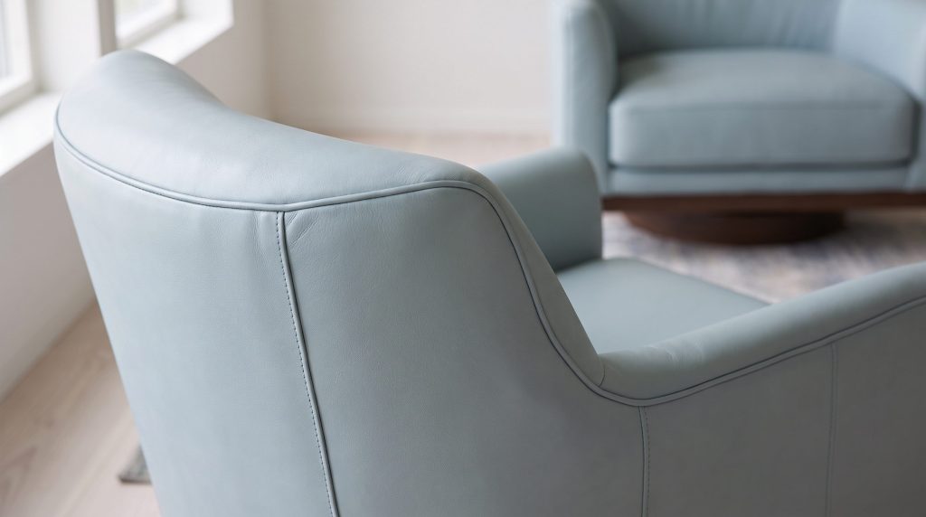 Close-up of soft light blue leather over the curved back and arm of a swivel chair