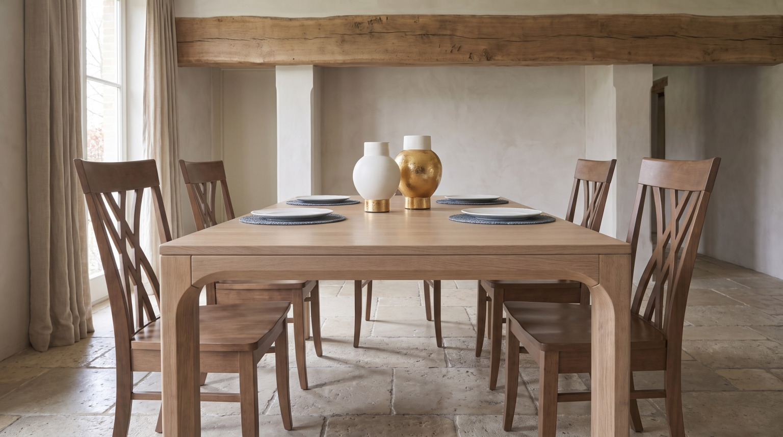 A brown maple dining table laid for four with slat-back chairs on an old stone floor