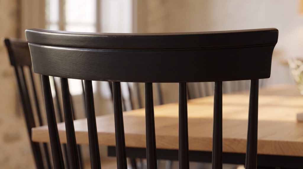 Close-up of the turned spindles and shaped crest rail of a black painted dining chair against the oak table