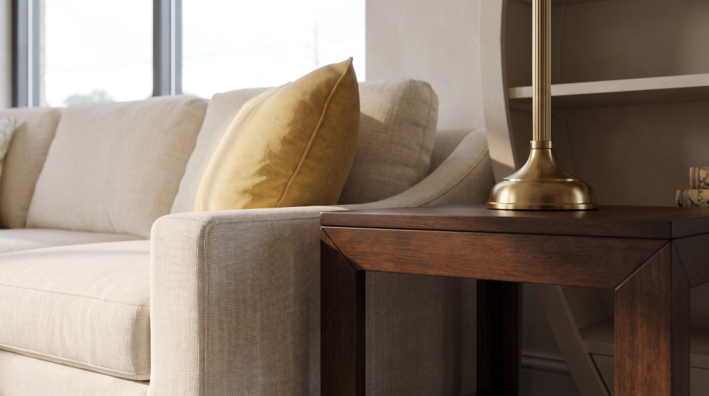 Close-up of an oatmeal woven sofa arm and mustard pillow against a dark walnut table edge and brass lamp base