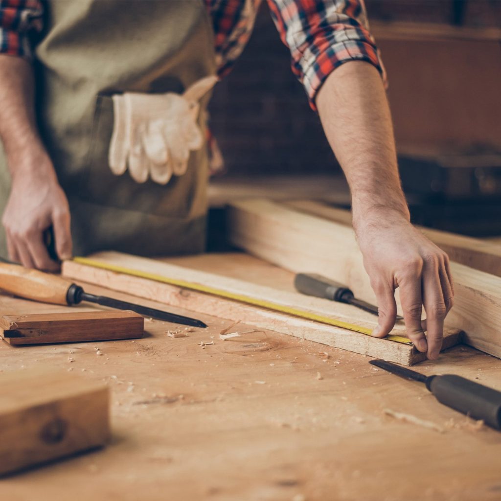 A craftsman measuring hardwood before cutting