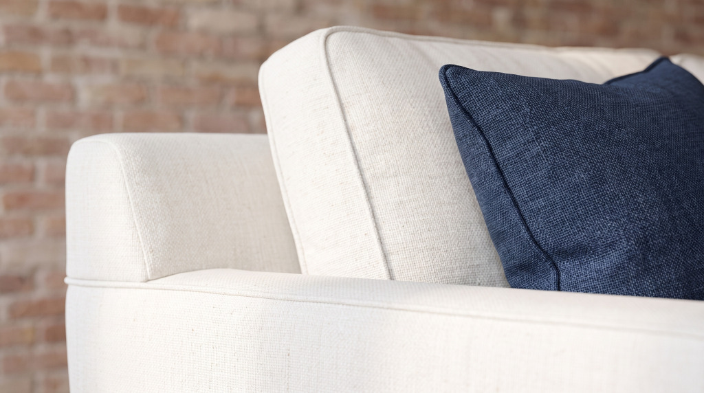 A close view of an ivory woven sofa arm with a navy pillow resting against it
