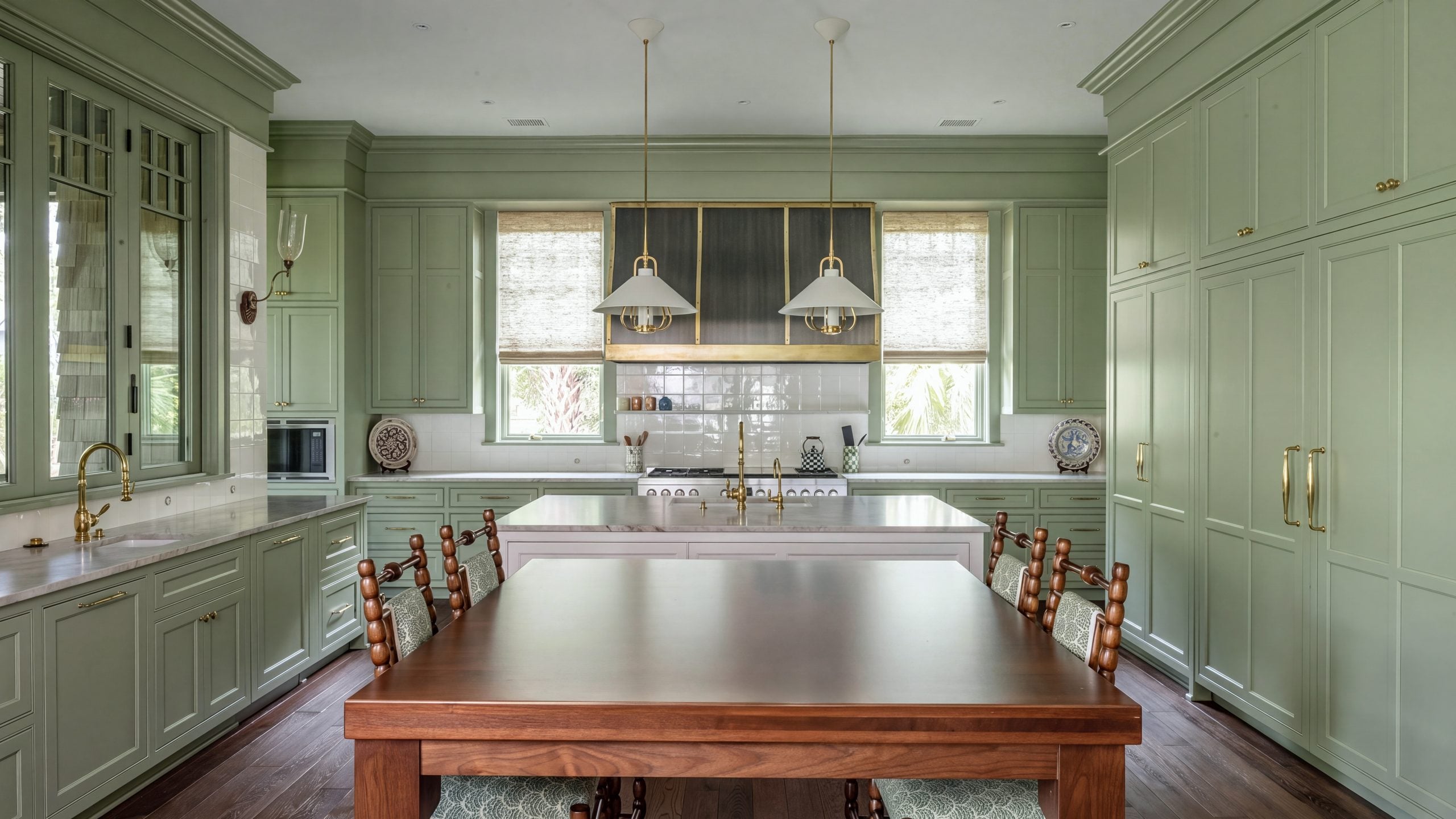 Kitchen and hood: Inset sage cabinetry around the range, a white island and a bronze hood strapped in brass.