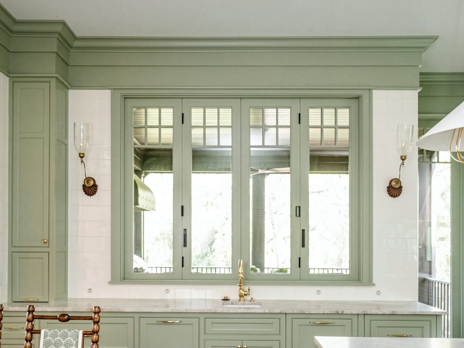 Pass-through window: Divided-light windows over the sink, framed in the same sage as the cabinets.