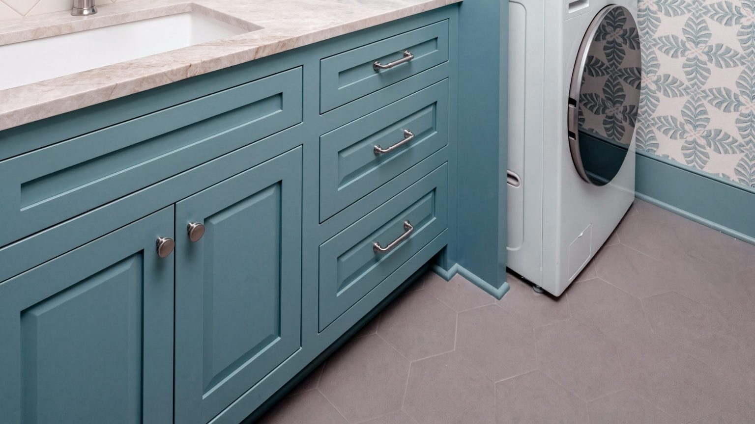 Sink run: Raised-panel doors and a drawer bank under the quartzite top.