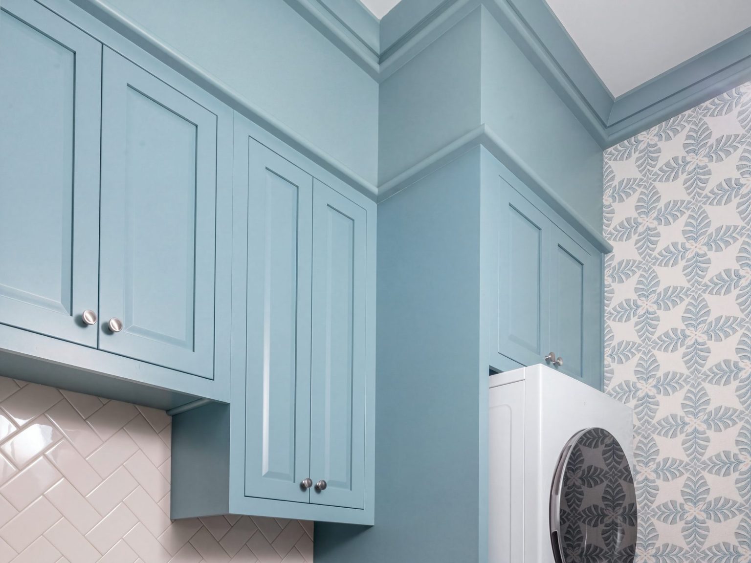 Upper cabinets: Uppers stepping around a tall column beside the stacked machines.