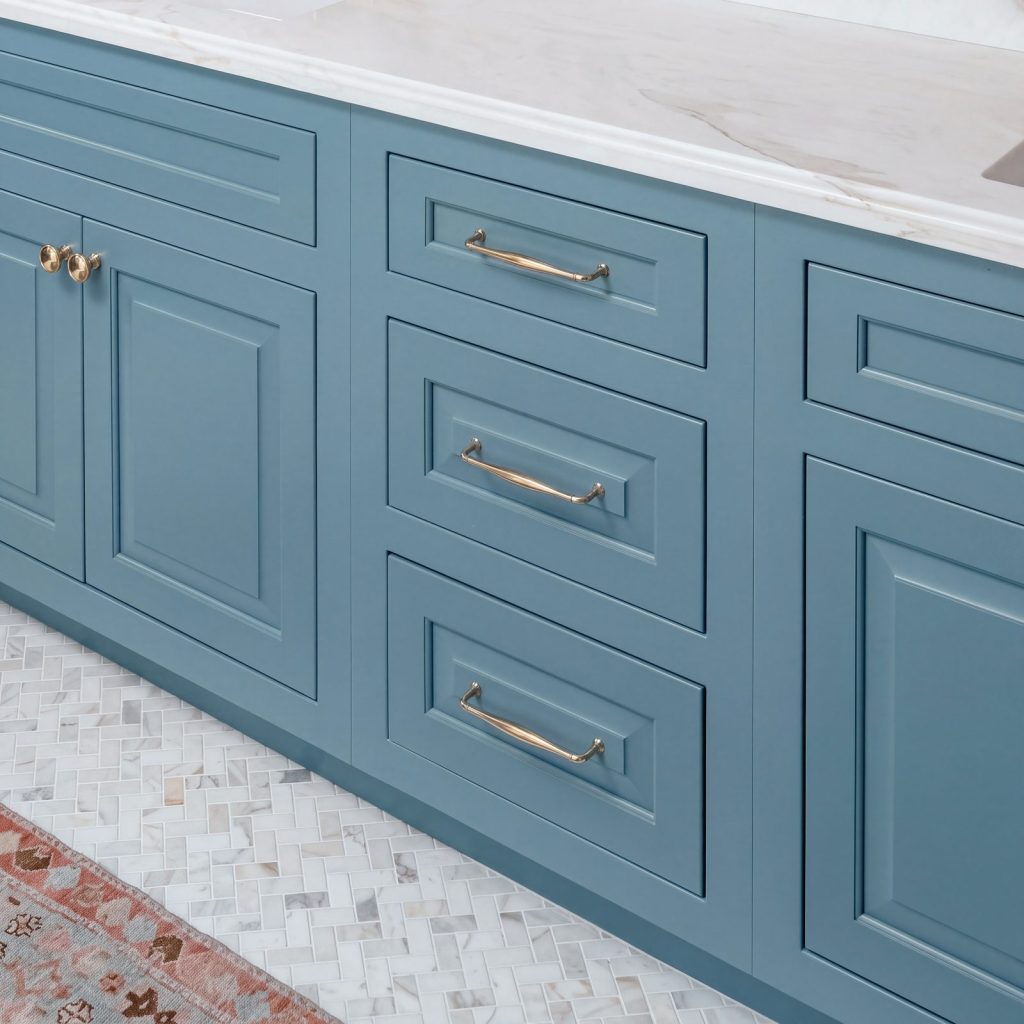 Inset drawers: Slate-blue inset drawers with brass pulls under a marble edge.