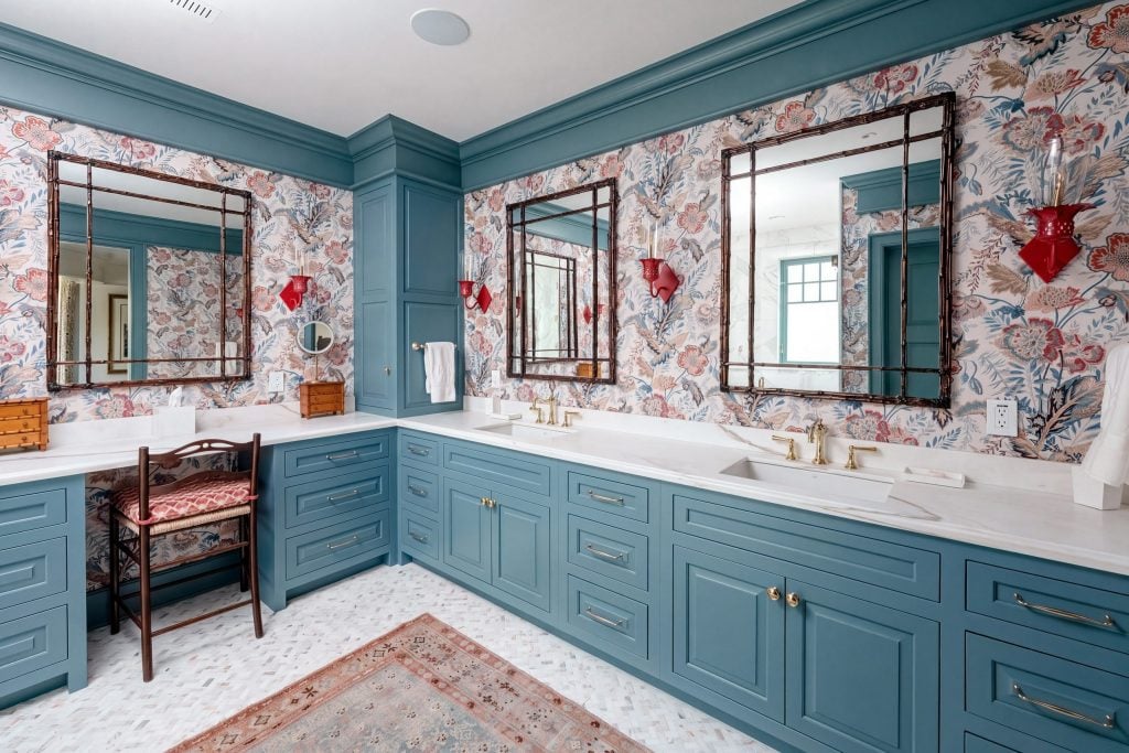 An L-shaped slate-blue bathroom vanity with inset drawers, brass pulls, a marble top, two sinks and a makeup station in a Kiawah Island bath.