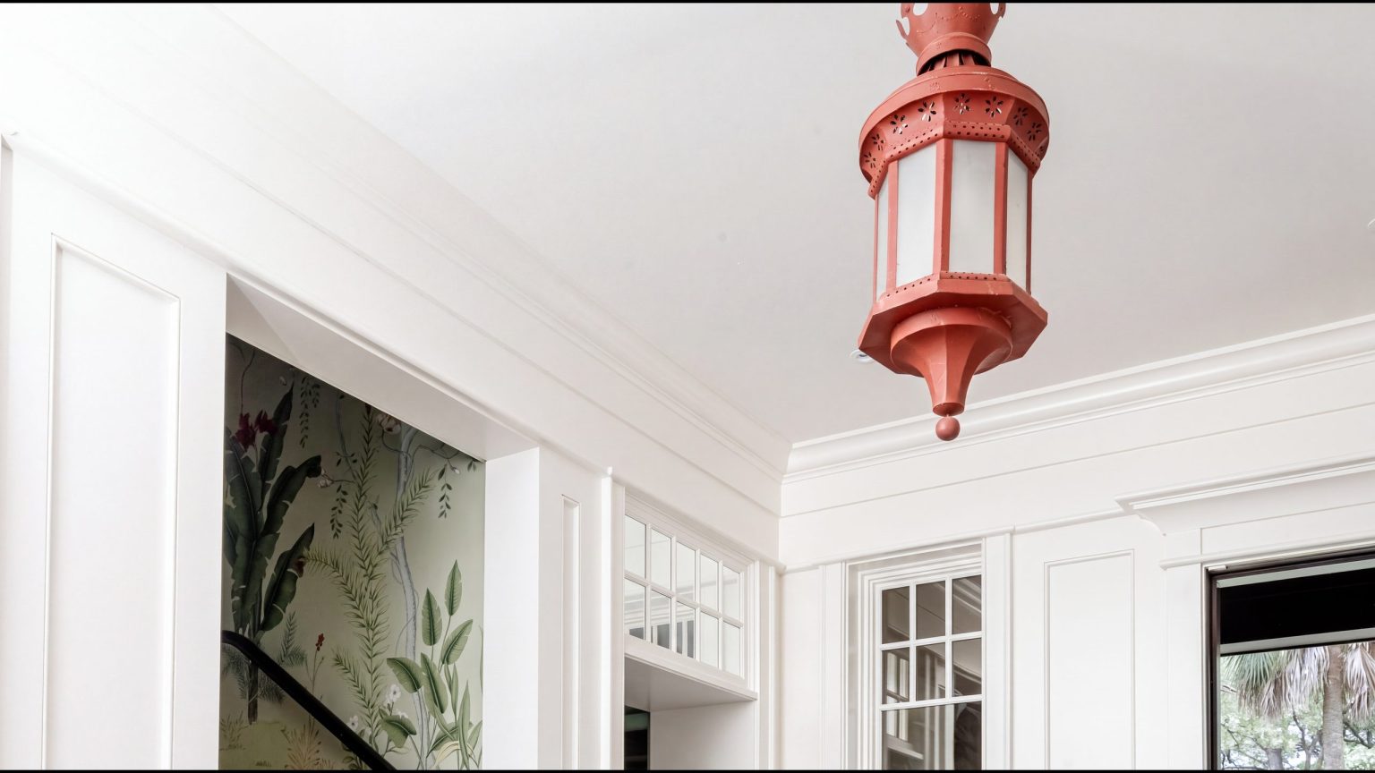 Crown and transoms: built-up crown molding, white panel millwork and divided transom windows around a red lantern in the entry hall.