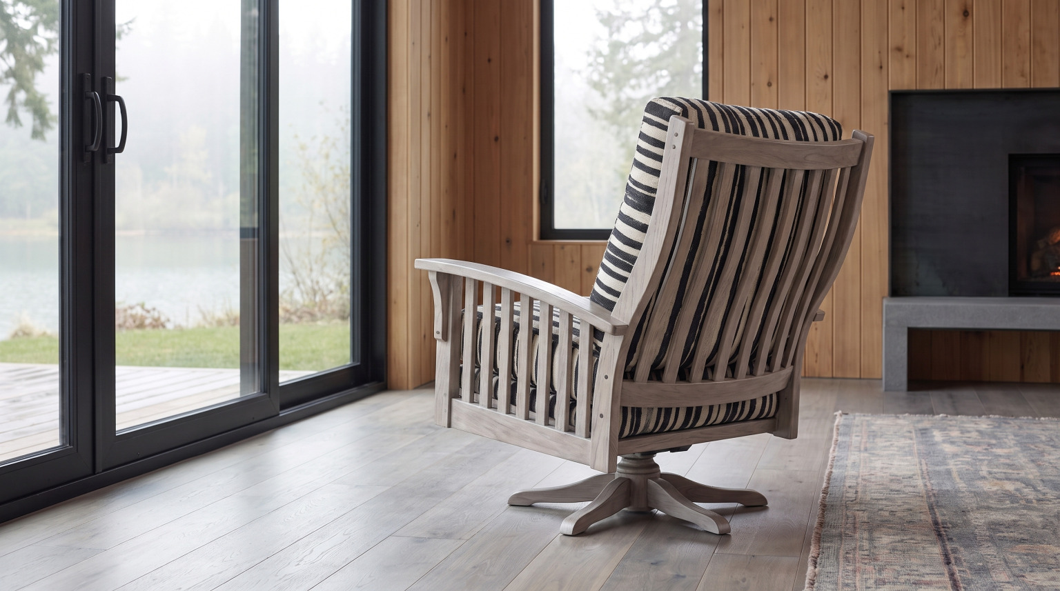 A slat-back swivel glider in weathered oak upholstered in a black and cream woven stripe