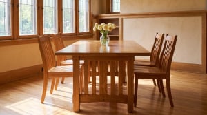 A Standard Mission trestle table in rustic quarter sawn white oak surrounded by slat-back dining chairs