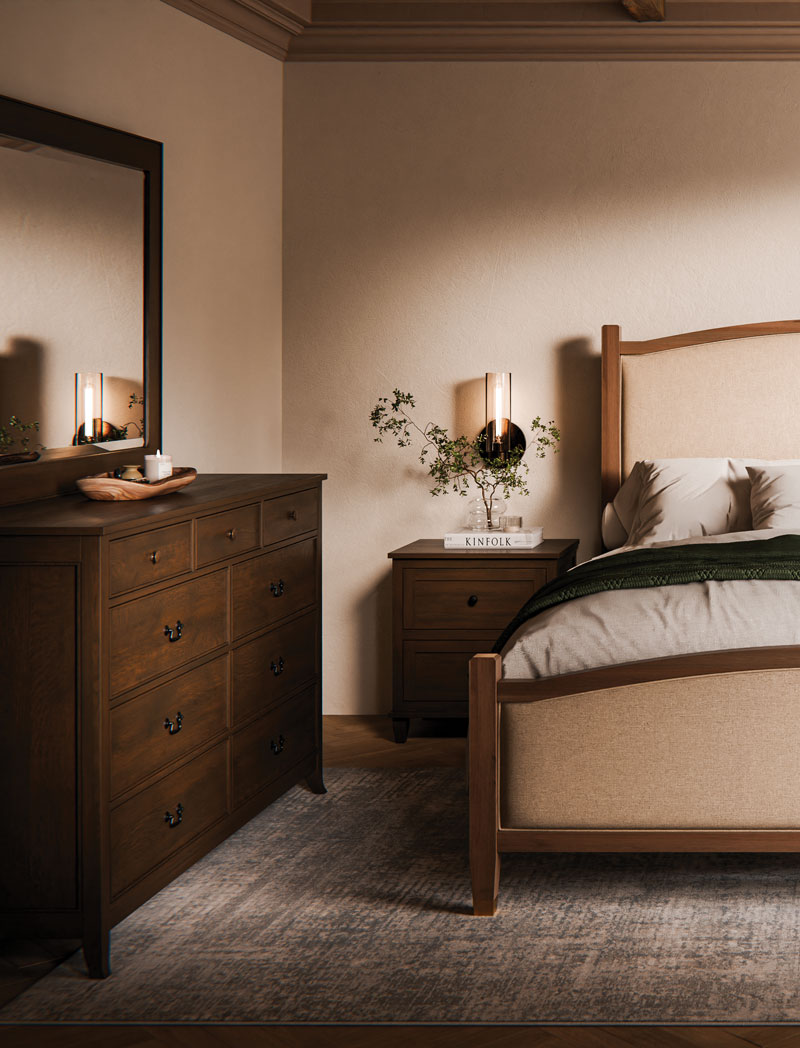 A solid hardwood chest of drawers and bed in a warm, lamplit bedroom