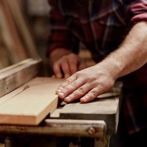 A craftsman running a hand along the edge of a freshly planed hardwood board