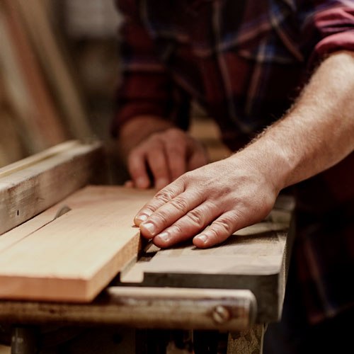 A craftsman running a hand along the edge of a freshly planed hardwood board