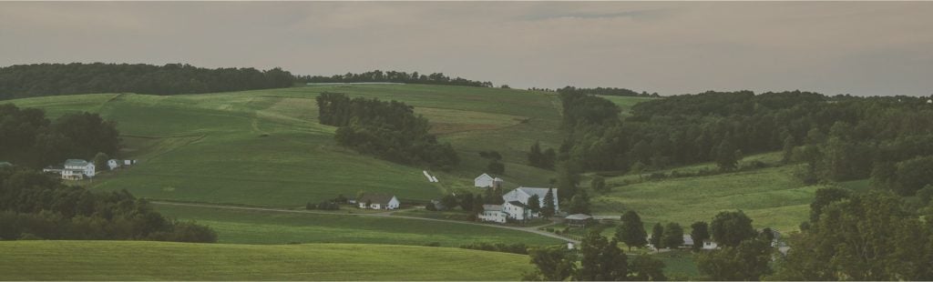 Rolling Ohio farmland with barns and treelines under low mist