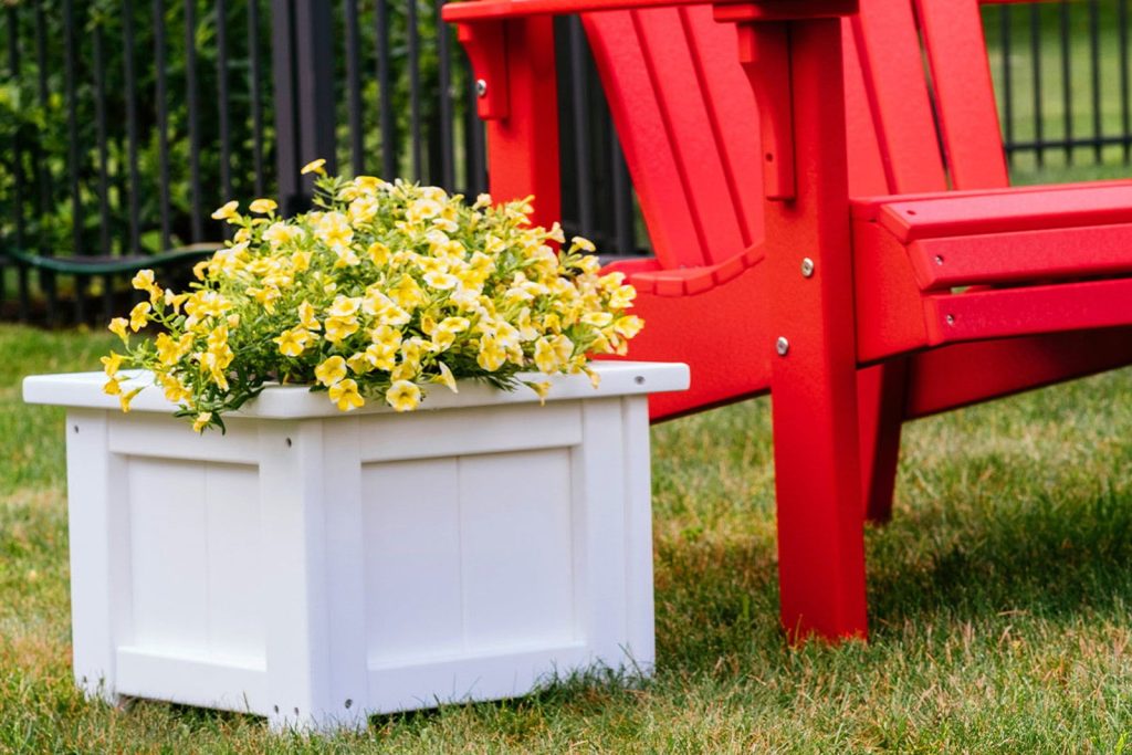A poly outdoor Adirondack chair beside a planter