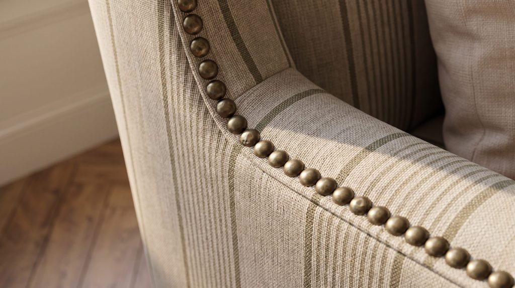Close-up of brass nailhead trim following the wing of a striped upholstered chair