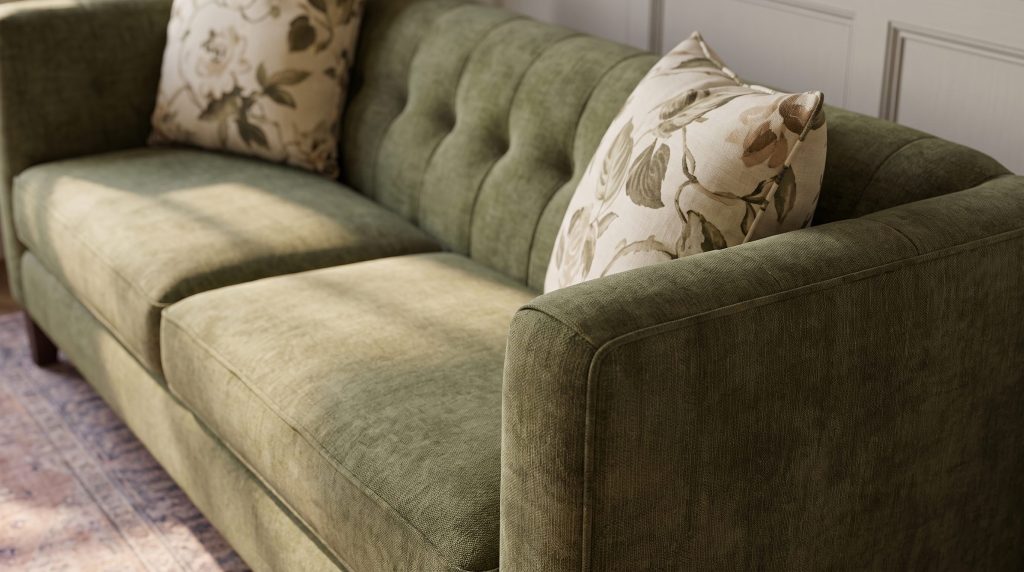 Close-up of button tufting across the back of an olive velvet sofa beside a floral pillow